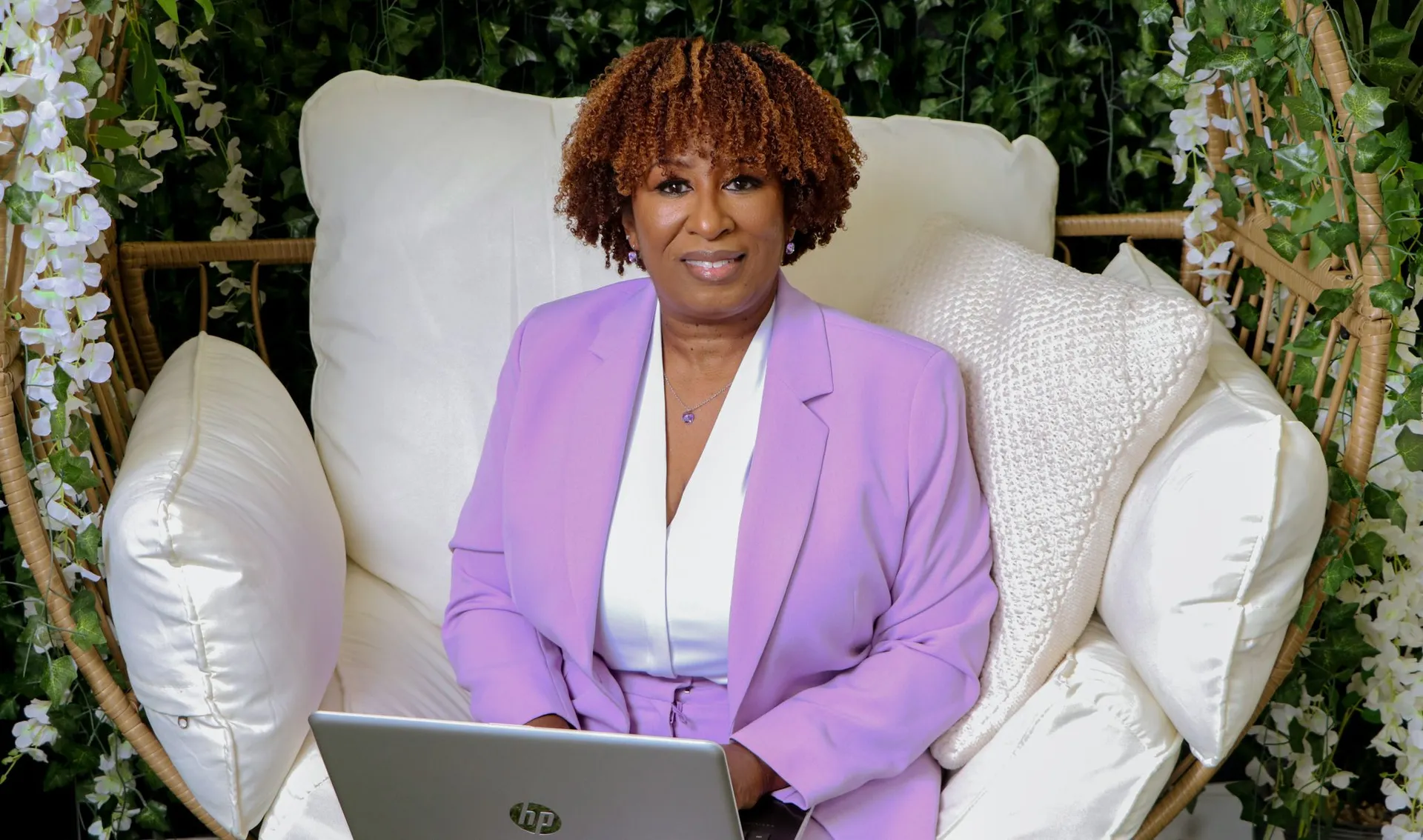 Founder seated in a wicker chair with a laptop
